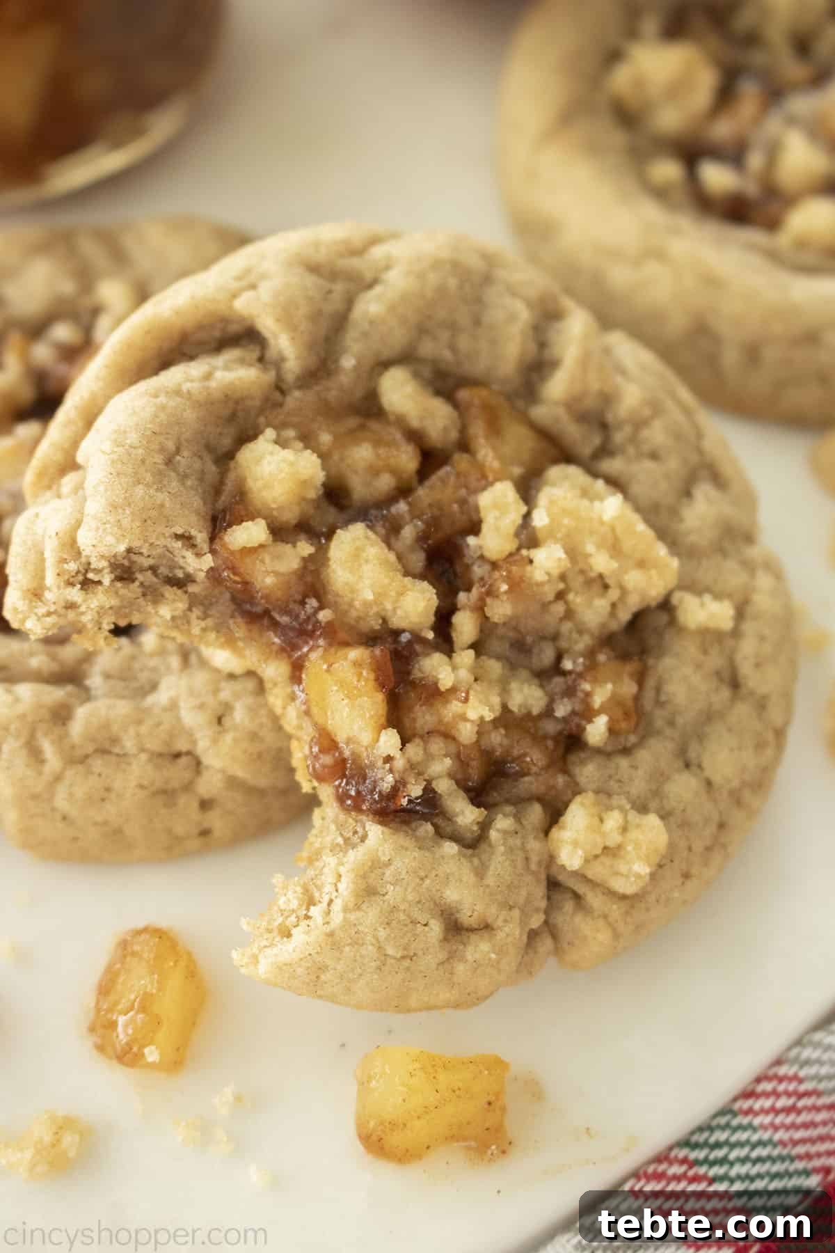 Apple Pie Cookie Recipe: Crispy, Cinnamon-Sugar Bites 3 Close up of bitten apple cookie. Showing the apple pie filling and crumb topping.