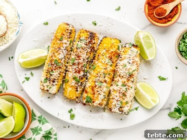 Four ears of Mexican street corn slathered in cheese and seasonings.