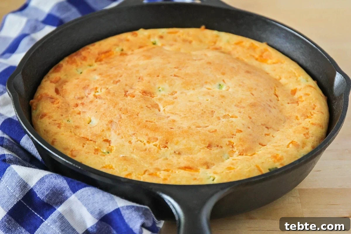 Mexican Cornbread recipe filled with diced jalapenos in a cast iron skillet.
