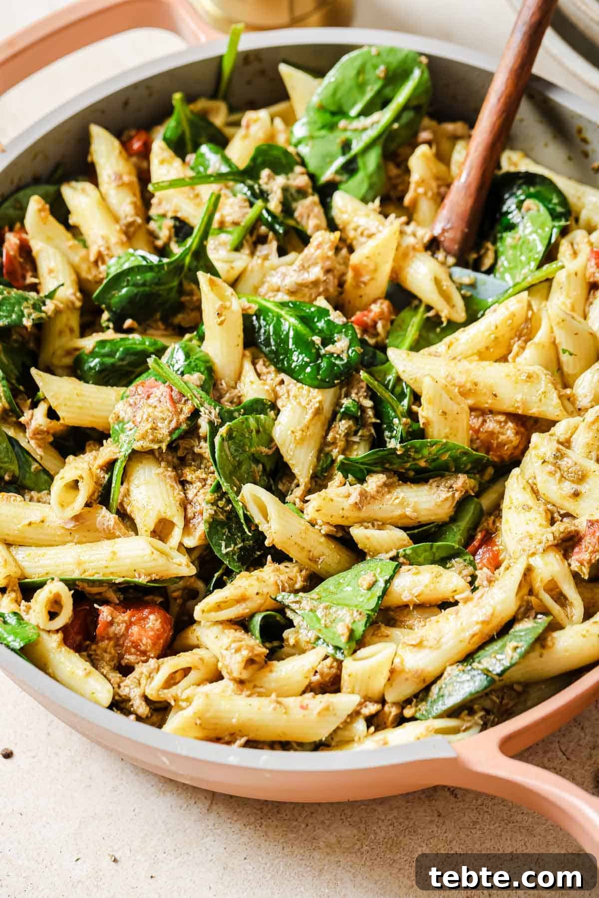 Creamy Tuna Pesto Pasta Recipe for Quick Weeknight Meals 2 Penne with cherry tomatoes, tuna, spinach and pesto in a skillet.