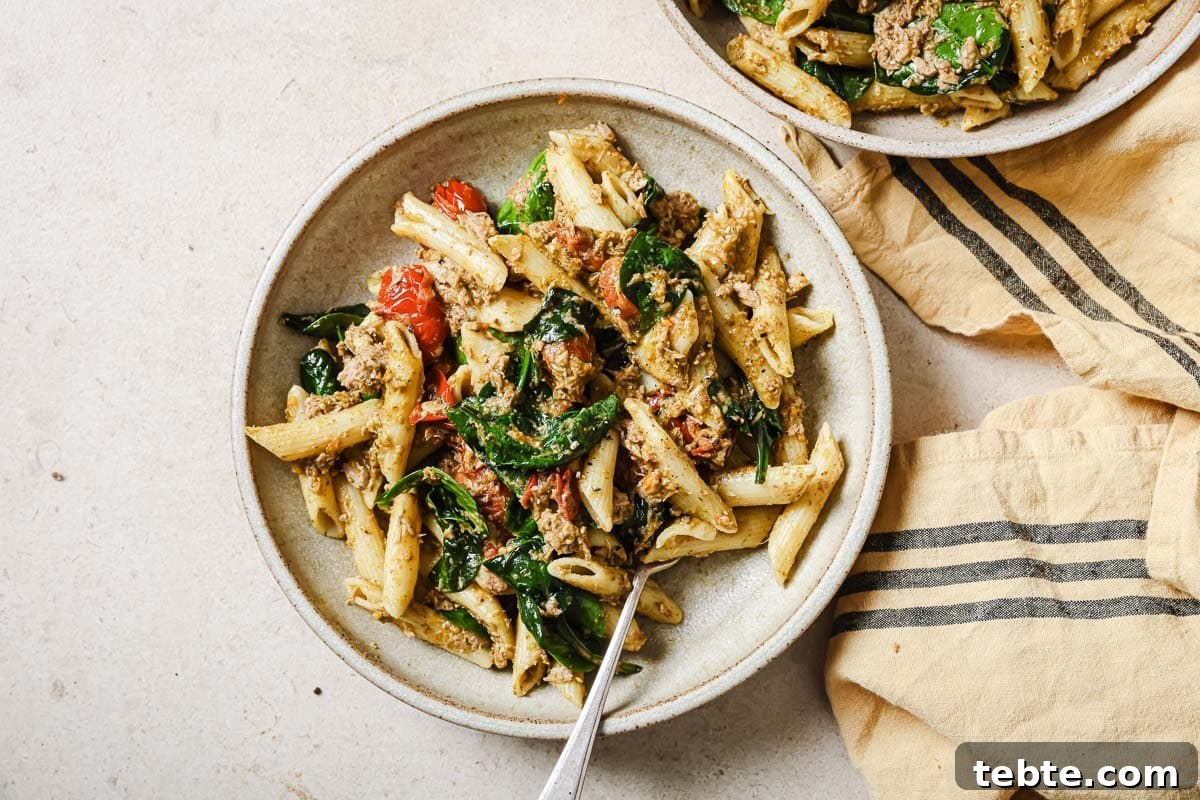 Creamy Tuna Pesto Pasta Recipe for Quick Weeknight Meals 12 Two bowls of pasta with spinach, tuna, pesto, and cherry tomatoes.