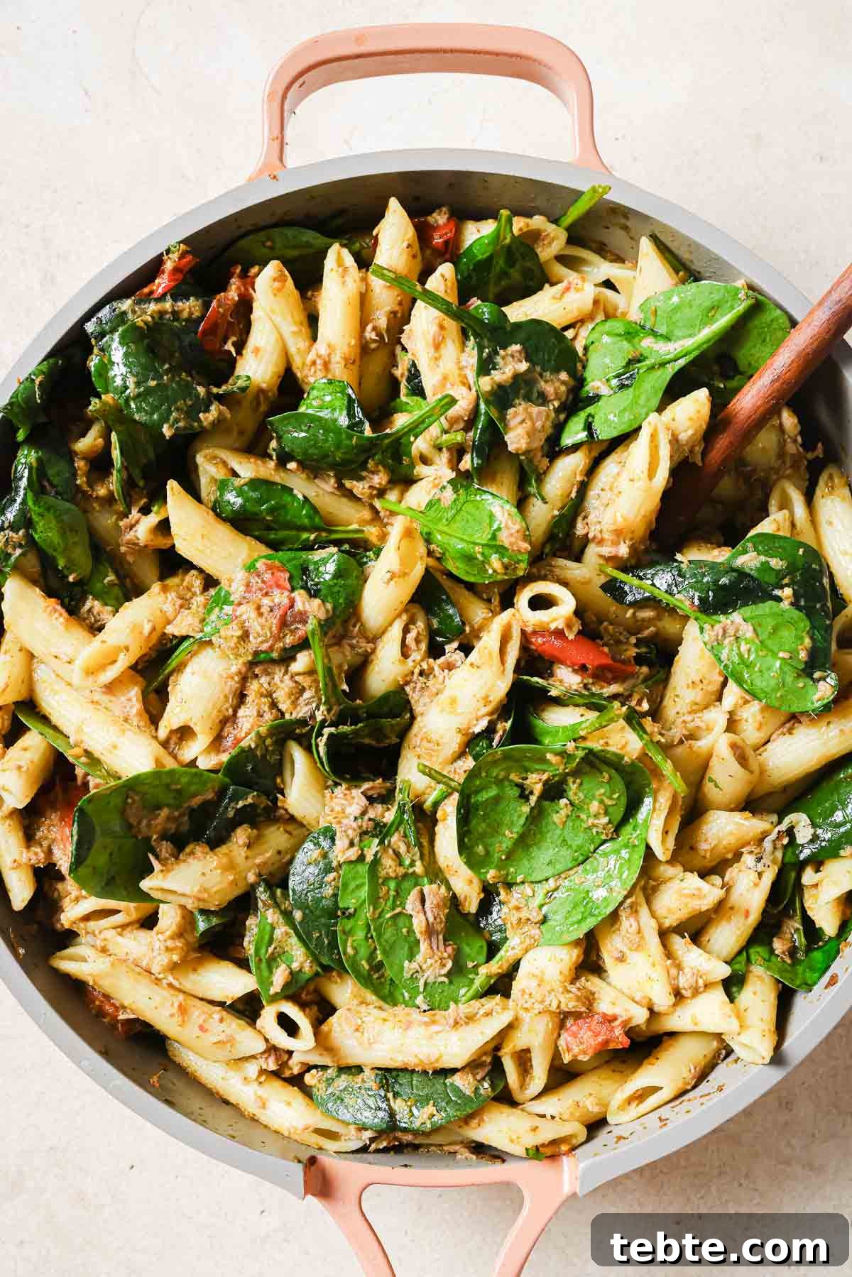 Creamy Tuna Pesto Pasta Recipe for Quick Weeknight Meals 9 A pan full of tuna pesto pasta with a wooden spoon.