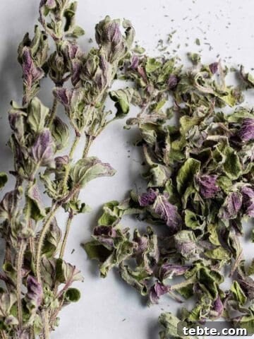 A bundle of dried oregano sprigs and a pile of dried oregano.