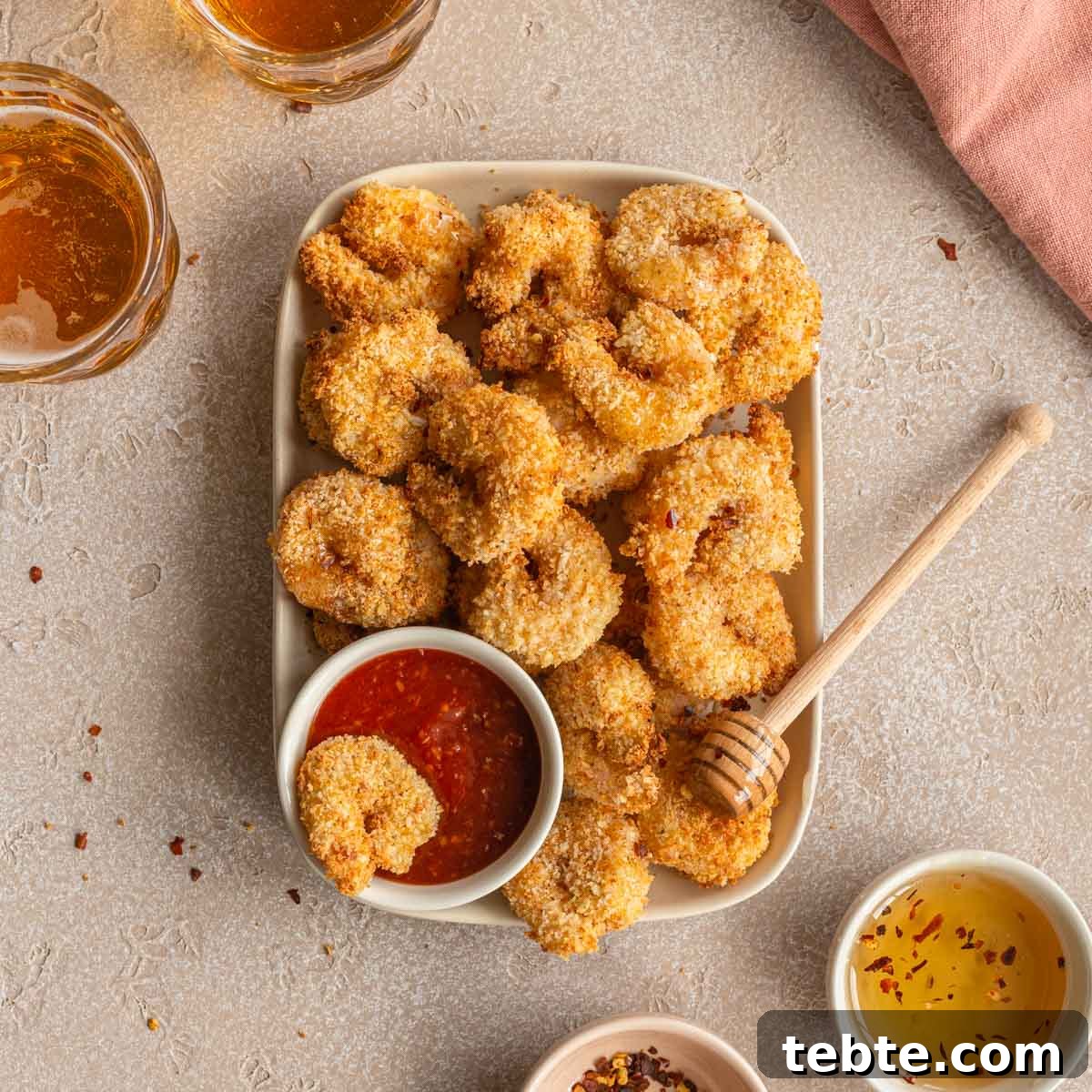 Crispy Air Fryer Breaded Shrimp Recipe for Quick Dinner 8 Overhead view of air fryer breaded shrimp on a plate with seafood sauce and a wooden honey dipper.