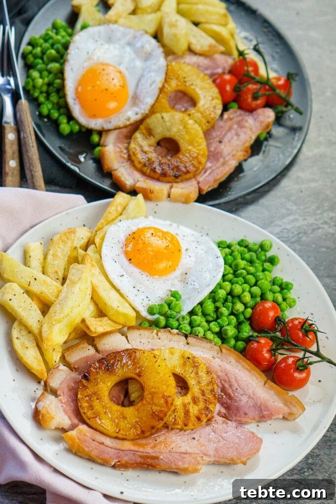 Classic Gammon Steak with Fried Egg and Chips 2 Two plates of ham egg and chips. Cooked gammon steaks served with chips, egg, peas, vine-ripened tomatoes and pineapple rings