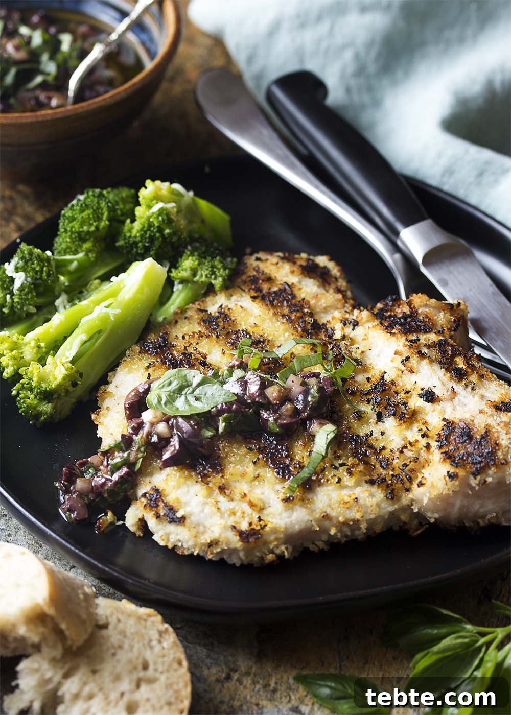 5 Must-Know Updates for June 2021 3 A grilled breaded pork chop on a plate topped with tapenade sauce.
