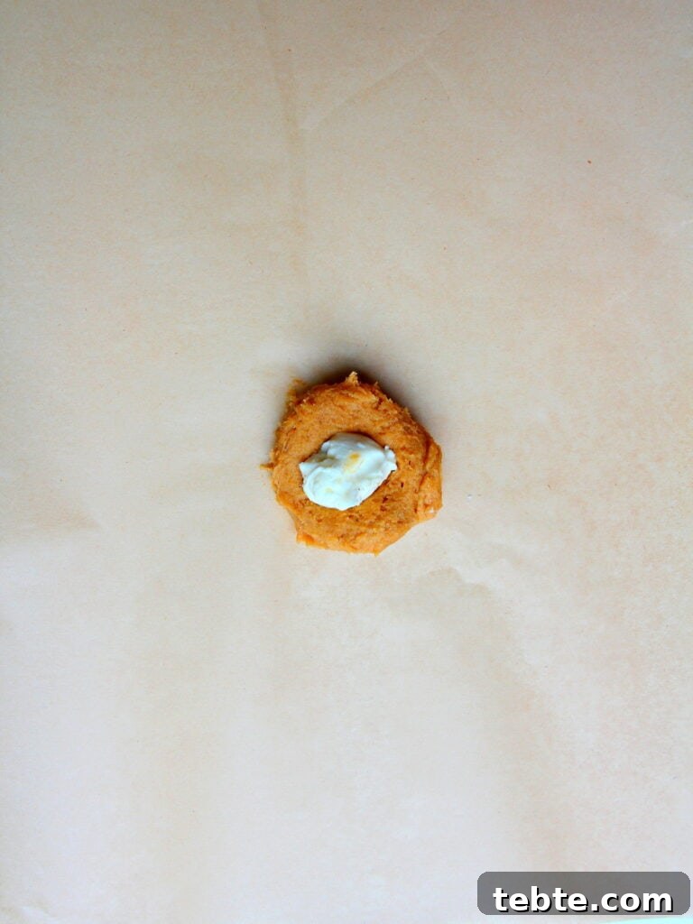 Pumpkin Cheesecake Cookies Recipe — Soft, Creamy Fall Treat 13 pumpkin cookie on brown parchment paper filled with cheesecake filling