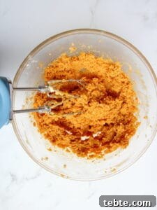 Pumpkin Cheesecake Cookies Recipe — Soft, Creamy Fall Treat 24 wet ingredients for pumpkin cookiescombined with electric mixer in transparent bowl