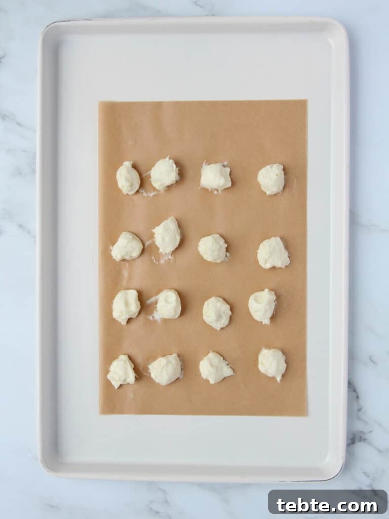 Pumpkin Cheesecake Cookies Recipe — Soft, Creamy Fall Treat 7 cheesecake filling dolloped onto brown parchment paper