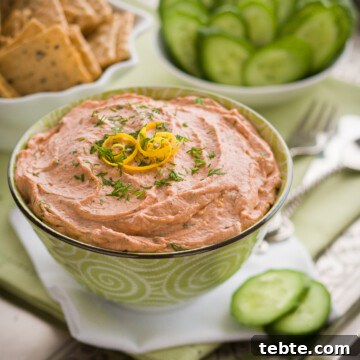 Creamy salmon dip on an appetizer tray with crackers and cucumber chips.