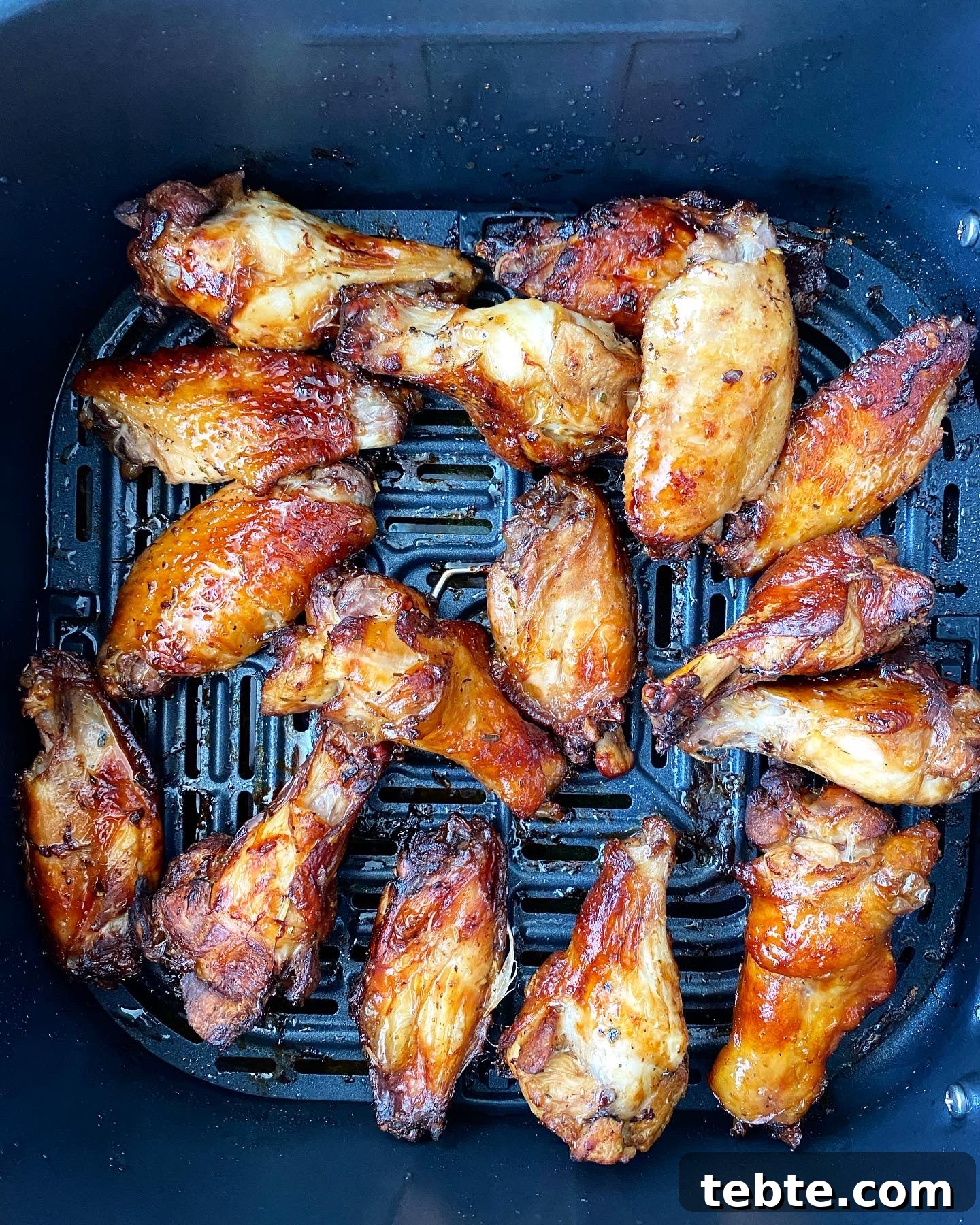 overhead shot of cooked marinated chicken wings in the air fryer basket