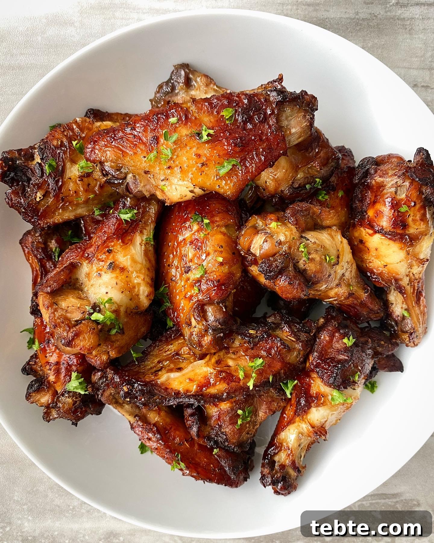 cooked marinated air fryer chicken garnished with parsley in a white bowl