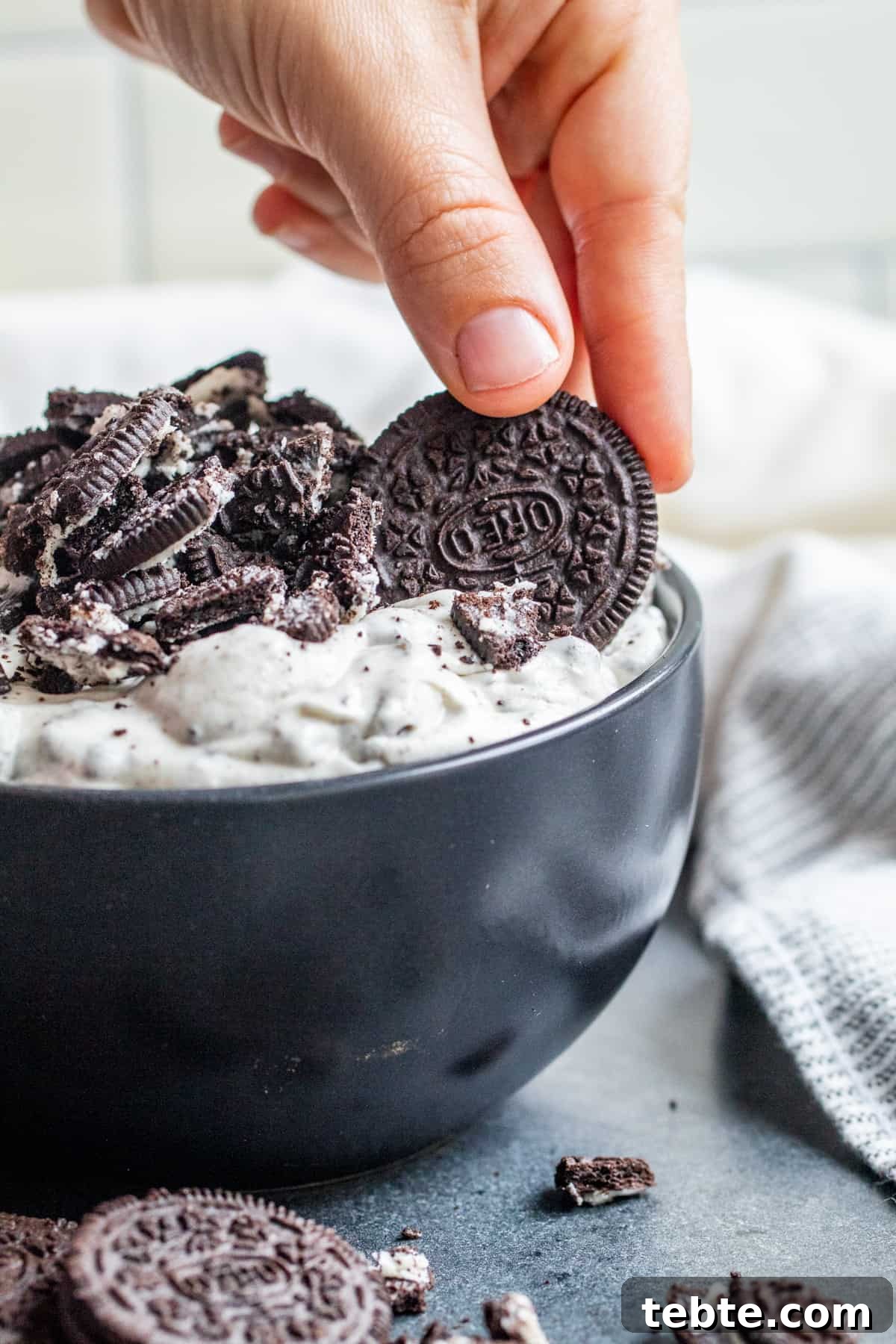 Creamy Oreo Dip Recipe for Parties and Dessert Tables 6 Hand dipping oreo cookie into dip.