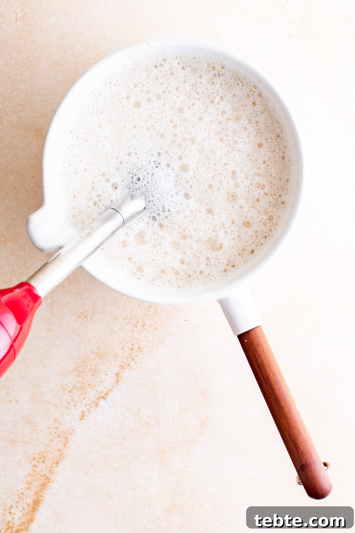 Refreshing Iced Chai Latte Recipe for Creamy Spiced Iced Tea 7 Top down view of milk being frothed in a pan.