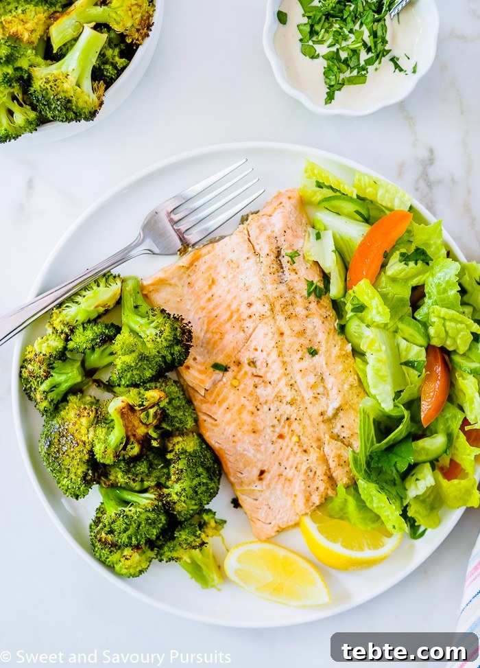 Baked Rainbow Trout Fillets with Roasted Broccoli and salad on dinner plate.