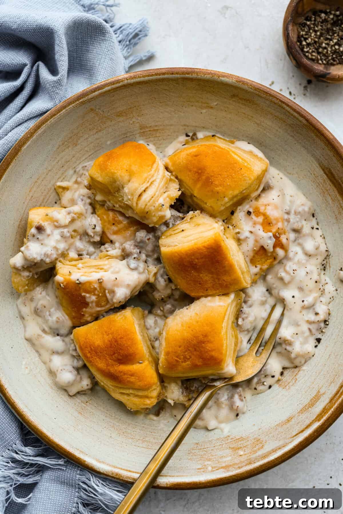 Forget the usual biscuits and gravy, this version takes everything you love and turns it into one irresistible, bubbly casserole. Creamy sausage gravy, buttery biscuits, and zero stress. Bowl with a serving of biscuits and gravy casserole.