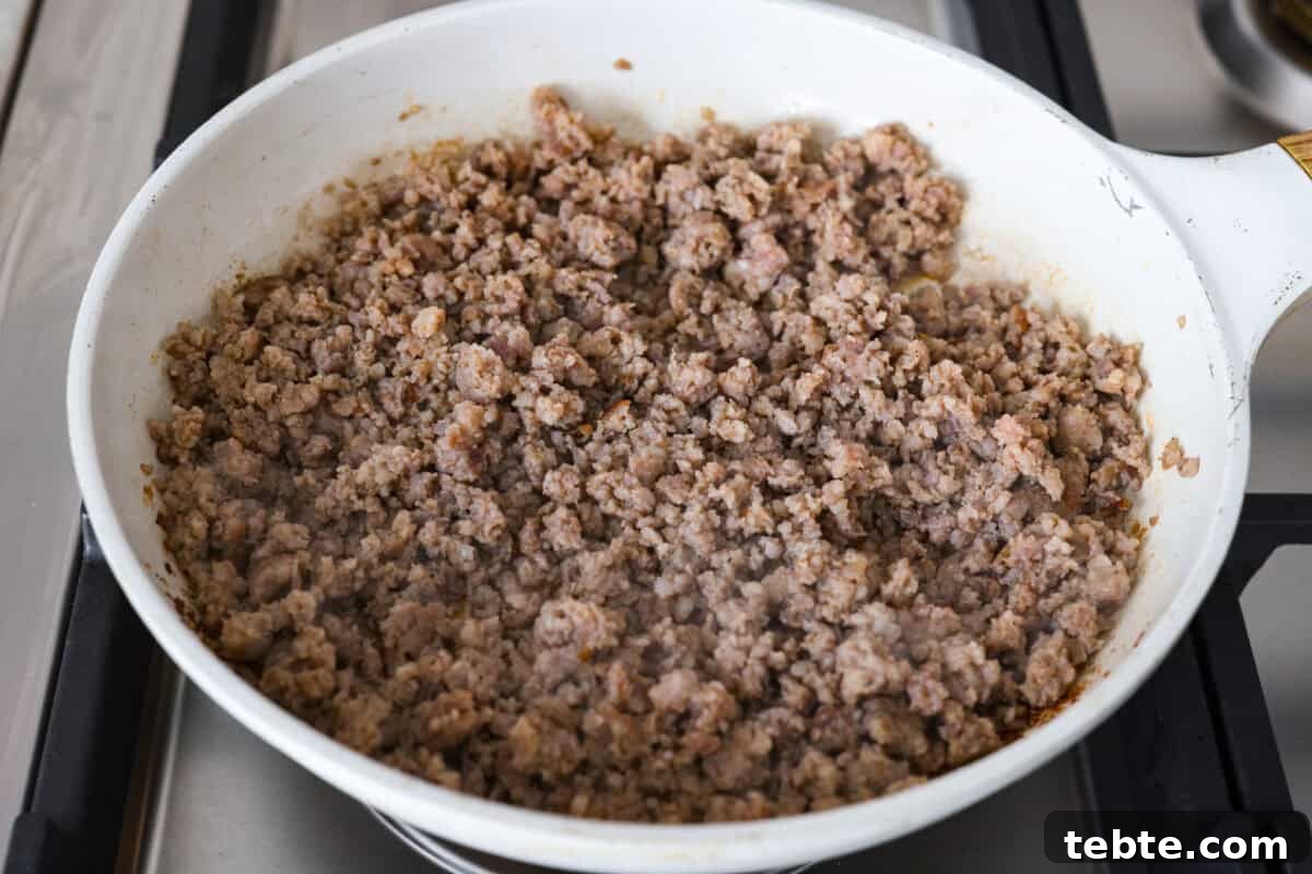 Forget the usual biscuits and gravy, this version takes everything you love and turns it into one irresistible, bubbly casserole. Creamy sausage gravy, buttery biscuits, and zero stress. Sausage cooking in a skillet.