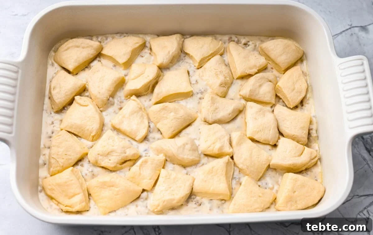 Forget the usual biscuits and gravy, this version takes everything you love and turns it into one irresistible, bubbly casserole. Creamy sausage gravy, buttery biscuits, and zero stress. Pieces of the cut up biscuits on top of the sausage gravy.