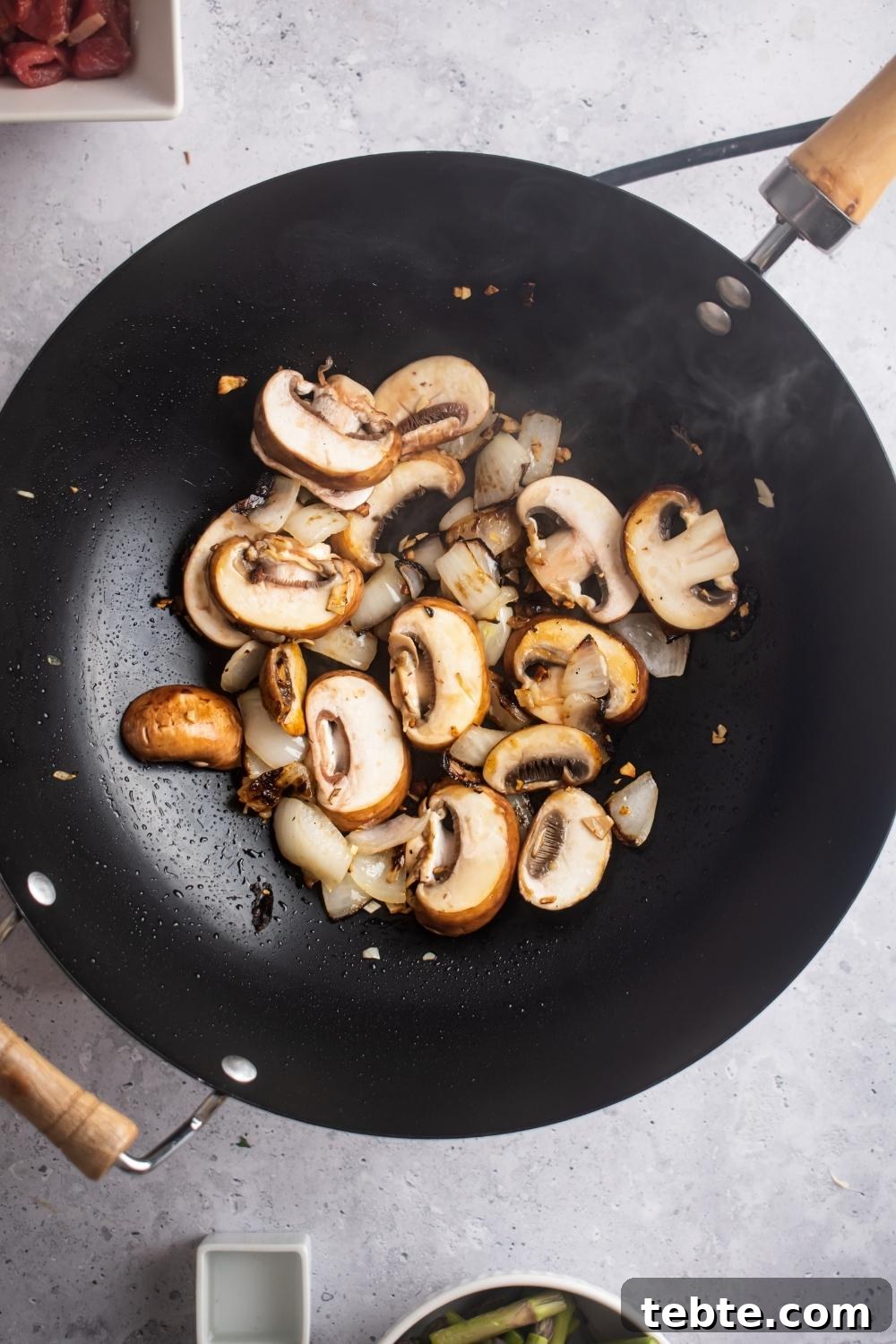 Panda Express Black Pepper Angus Steak Copycat Recipe 6 An overhead view of a hot wok cooking mushrooms.