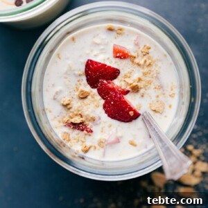 Finished strawberry cheesecake overnight oats, topped with fresh strawberries, ready for a delicious breakfast.