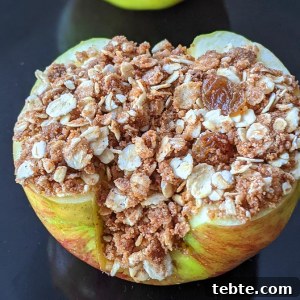 Crispy Air Fryer Baked Apples with Cinnamon and Honey 7 closeup photo showing an air fryer baked apple with an oat-based crumble filling with cinnamon, raisins and pecans