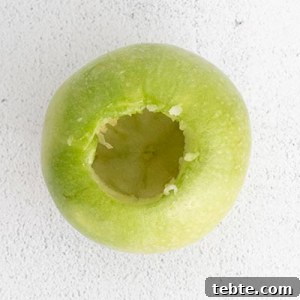 Crispy Air Fryer Baked Apples with Cinnamon and Honey 8 process photo showing a bright green apple that has been cored to make air fryer baked apples
