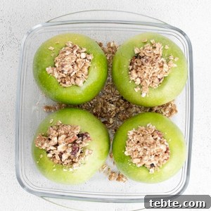 Crispy Air Fryer Baked Apples with Cinnamon and Honey 10 process photo of four apples with an oat-based crumble filling inside each apple ready to be made in the air fryer.