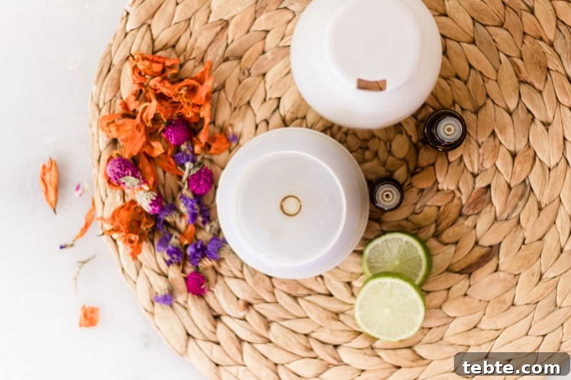 Tropical Essential Oil Diffuser Blends for Uplifting Scents 3 Diffuser with bright flowers and lime slices around it.