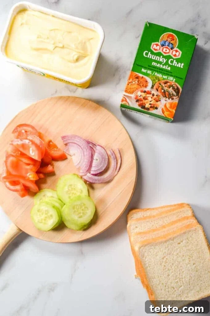 5-Minute Masala Sandwich Recipe: Spicy Indian Toasted Sandwich 5 Margarine, chaat masala, a cutting board with sliced vegetables, and sandwich bread