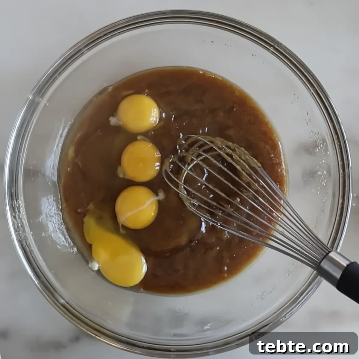 Gluten-Free Flag Cookie Cake Recipe for Patriotic Celebrations 7 eggs and egg yolks on top of brown thick mixture in glass bowl.