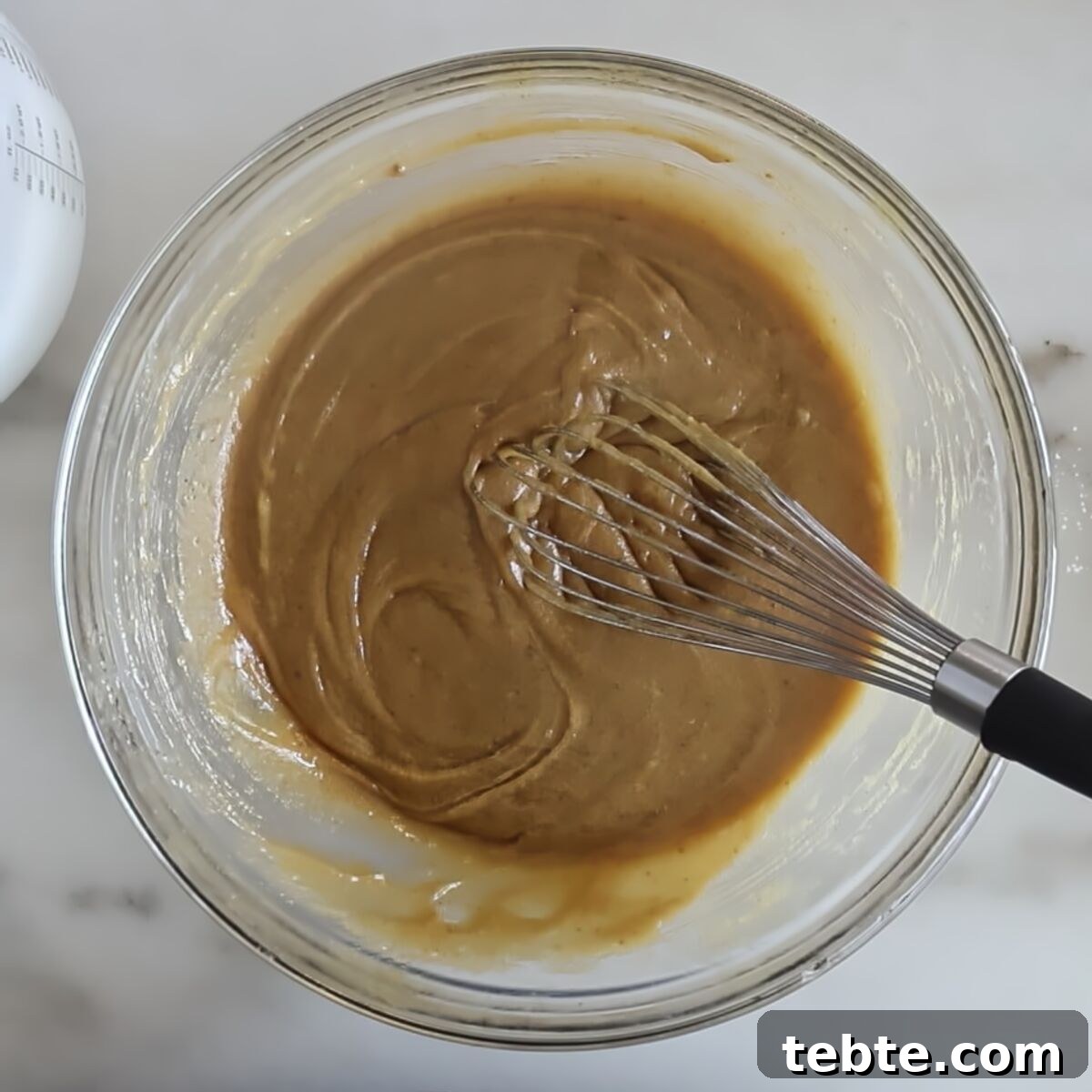 Gluten-Free Flag Cookie Cake Recipe for Patriotic Celebrations 8 light brown mixture in glass bowl with whisk.