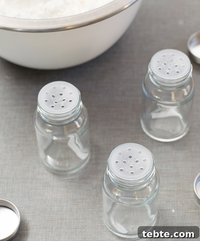 How to Make Natural DIY Body Powder at Home 6 Three empty glass bottle jars placed on a light grayish table near the stainless mixing bowl