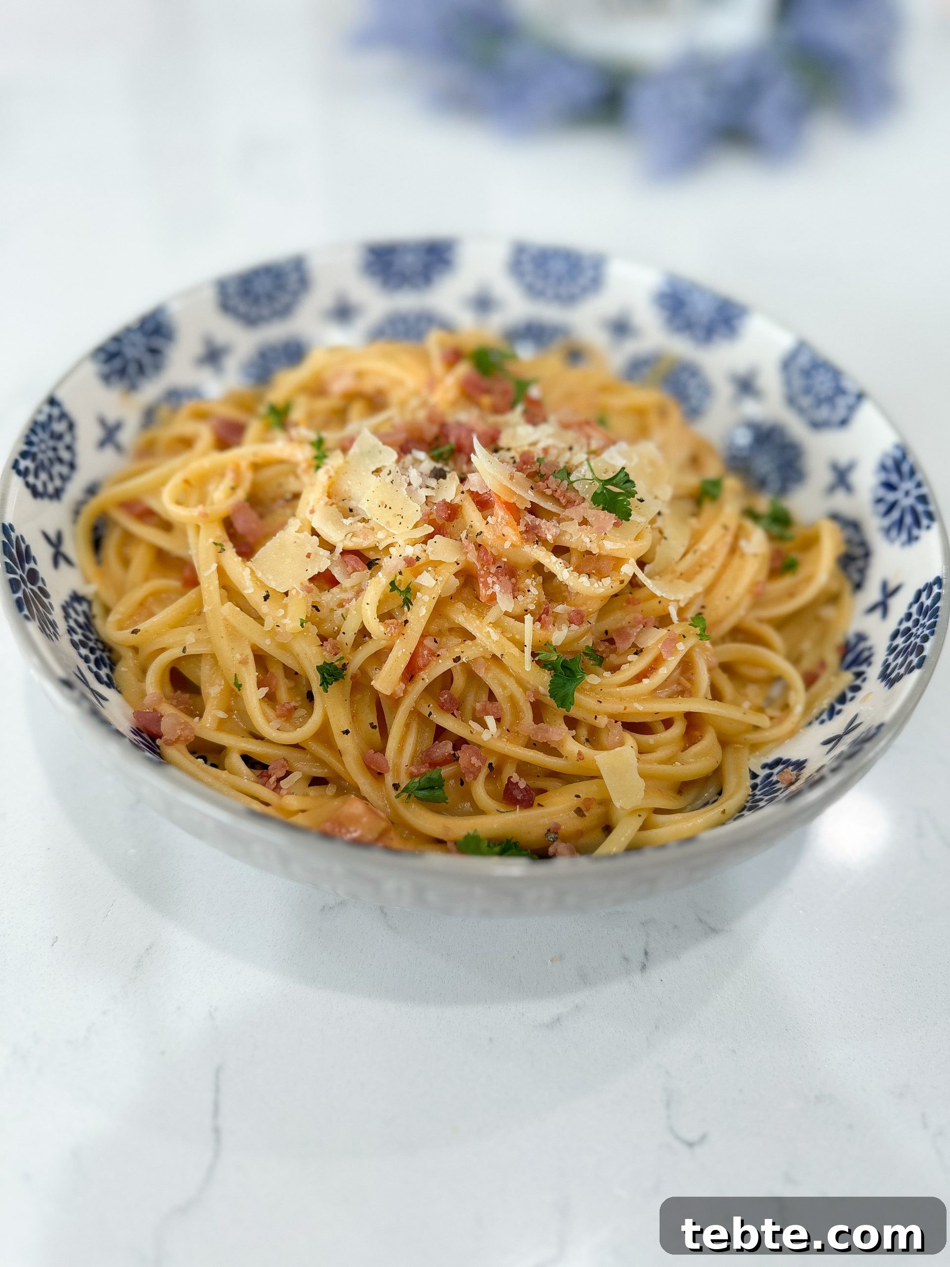 Creamy Tomato and Bacon Pasta Recipe for Weeknight Dinners 2 Creamy tomato bacon pasta in a white bowl with fettuccine noodles and bacon bits