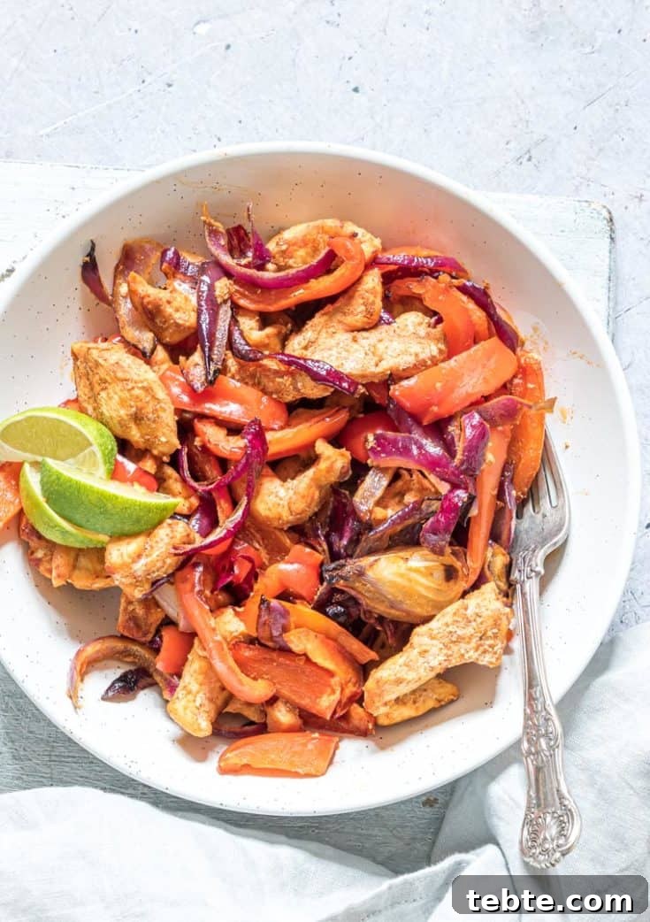 air fryer chicken fajitas served as a salad in a white bowl with fork and lime slices