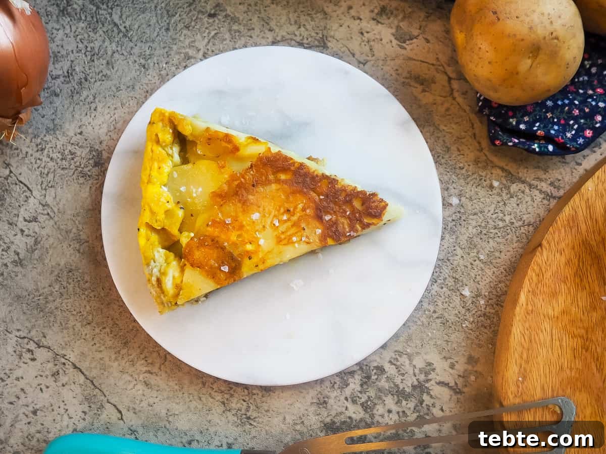Authentic Spanish Tortilla: Traditional Egg and Potato Recipe 10 A slice of Spanish tortilla on a marble plate.