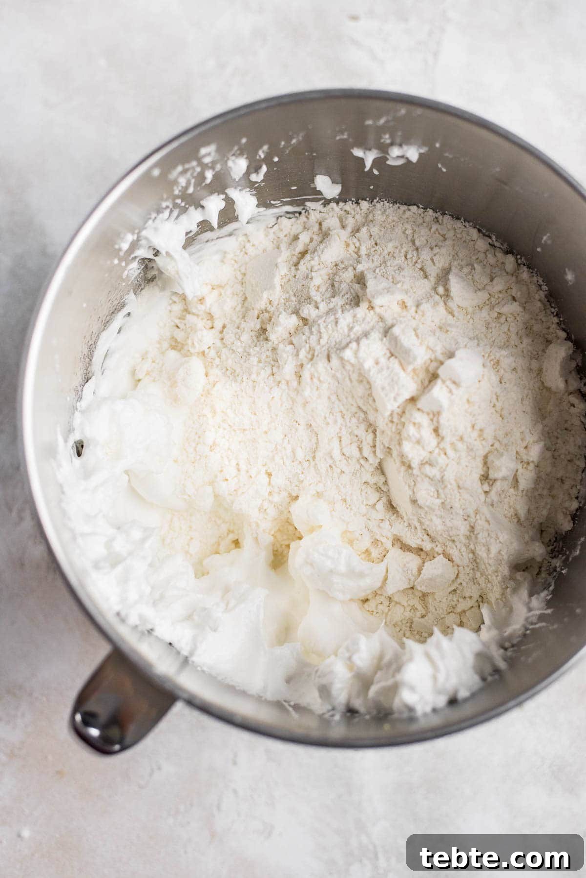 adding almond flour and powdered sugar to meringue