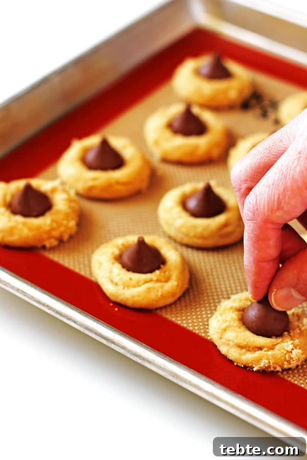 Peanut Butter Kiss Cookies Recipe — Chewy Chocolate-Stamped Treats 6 Placing kiss candy on top of baked cookies