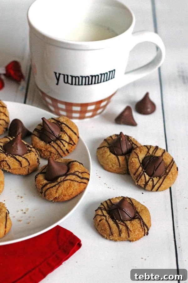 Peanut Butter Kiss Cookies Recipe — Chewy Chocolate-Stamped Treats 8 Peanut Butter Kiss Cookies on plate with a mug filled with milk