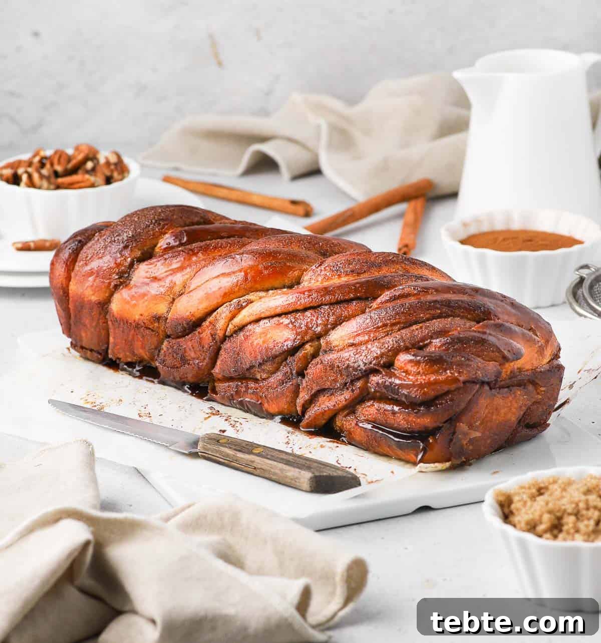 Cinnamon Babka Recipe: Soft, Swirled Brioche Loaf 4 Side view on the bread on a white ceramic board.
