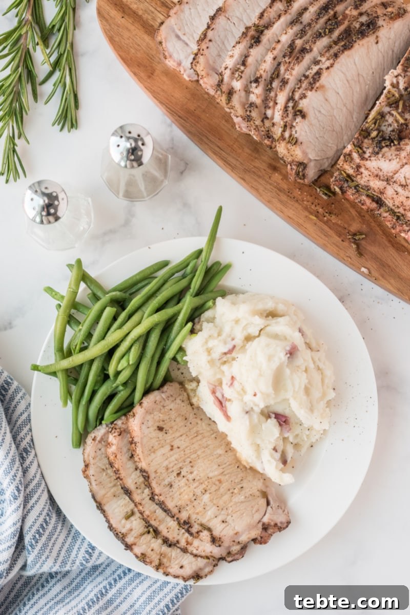 Rosemary Pork Roast sliced pork roast on plate with green beans and potatoes