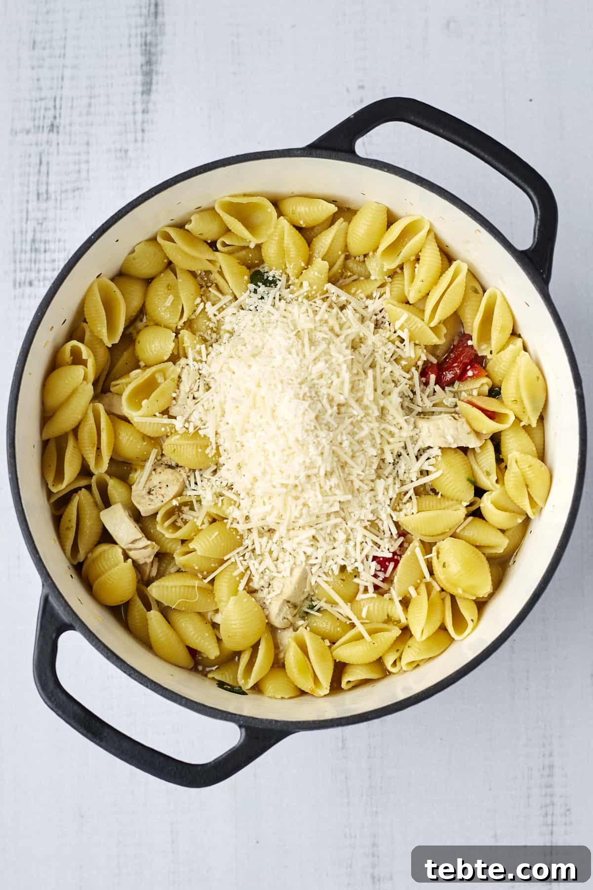 Creamy Tuscan Chicken Pasta Made in One Pot 6 Freshly grated Parmesan on top of creamy tuscan chicken pasta in a large pot.