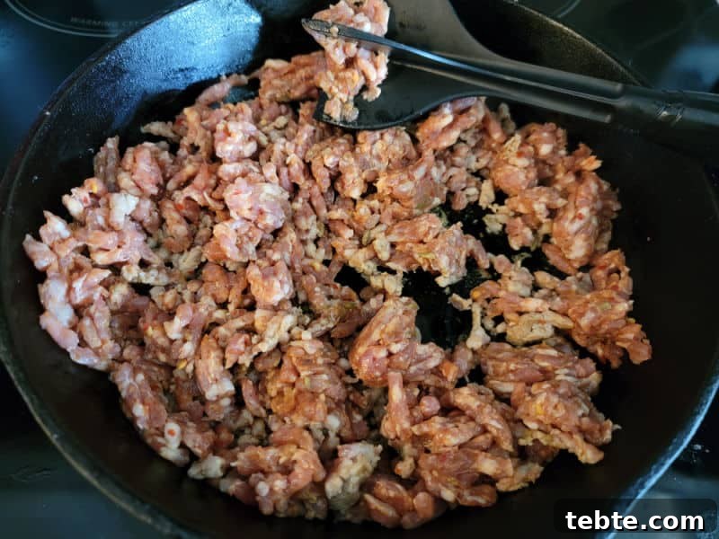 3-Ingredient Rotel and Sausage Dip Recipe 4 Italian sausage in a cast iron skillet with a mix n chop