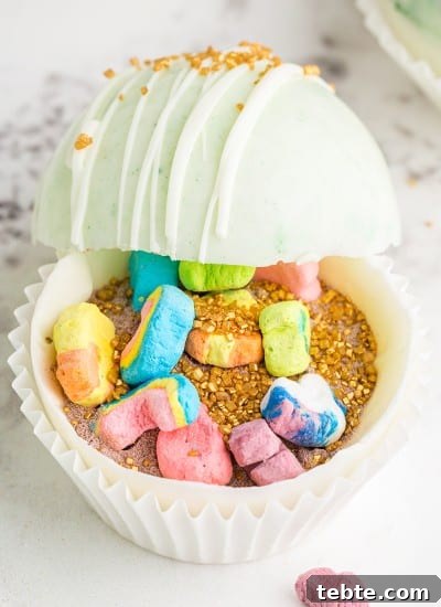 White and green marbled hot chocolate bombs propped open with gold sprinkles and Lucky Charms marshmallows inside