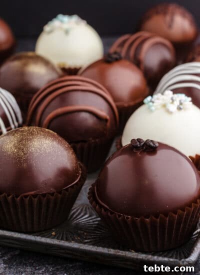 Sheet pan filled with a variety of differently decorated hot chocolate bombs.