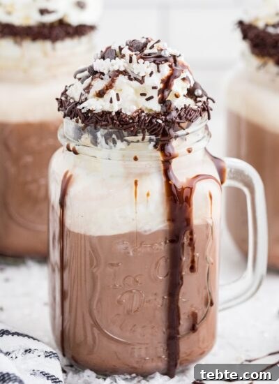 Dirty Snowman cocktail drink in a glass topped with whipped cream, sprinkles and chocolate syrup, with 2 other Dirty Snowman cups in the background, with text overlay.