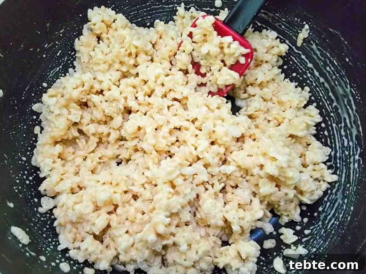 Small-Batch Rice Krispie Treats Recipe 6 rice Krispie's cereal mixed into marshmallow mixture in a pan.