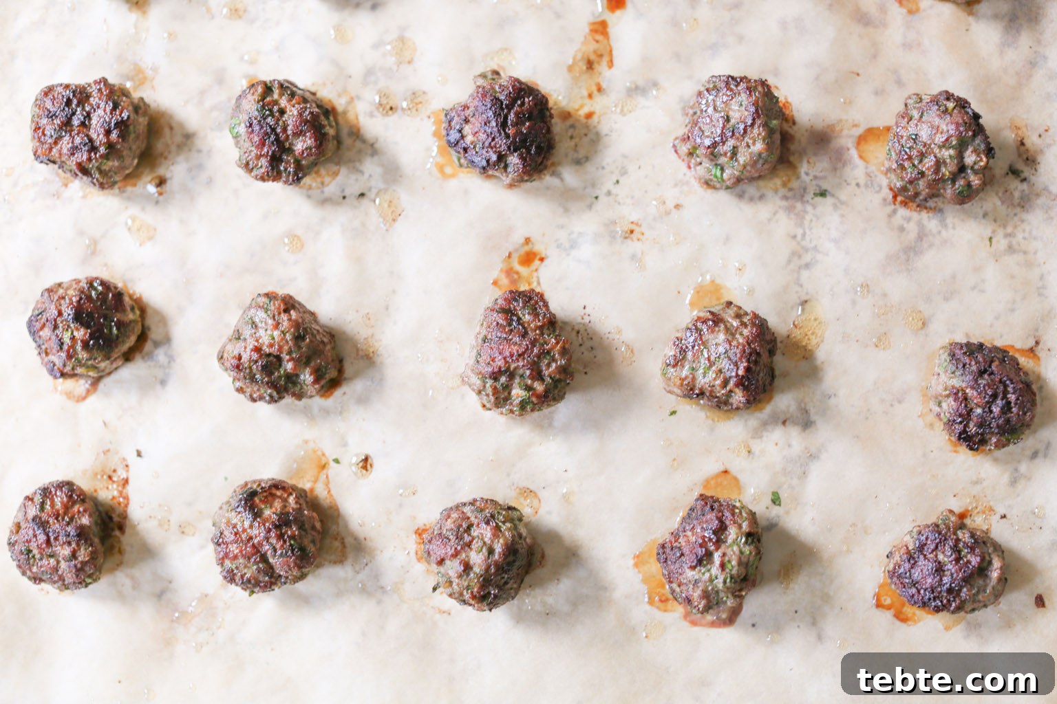 Spiced Lamb Kofta Recipe — Authentic Middle Eastern Meatballs 9 Lamb kofta on a baking sheet after being removed from the oven.