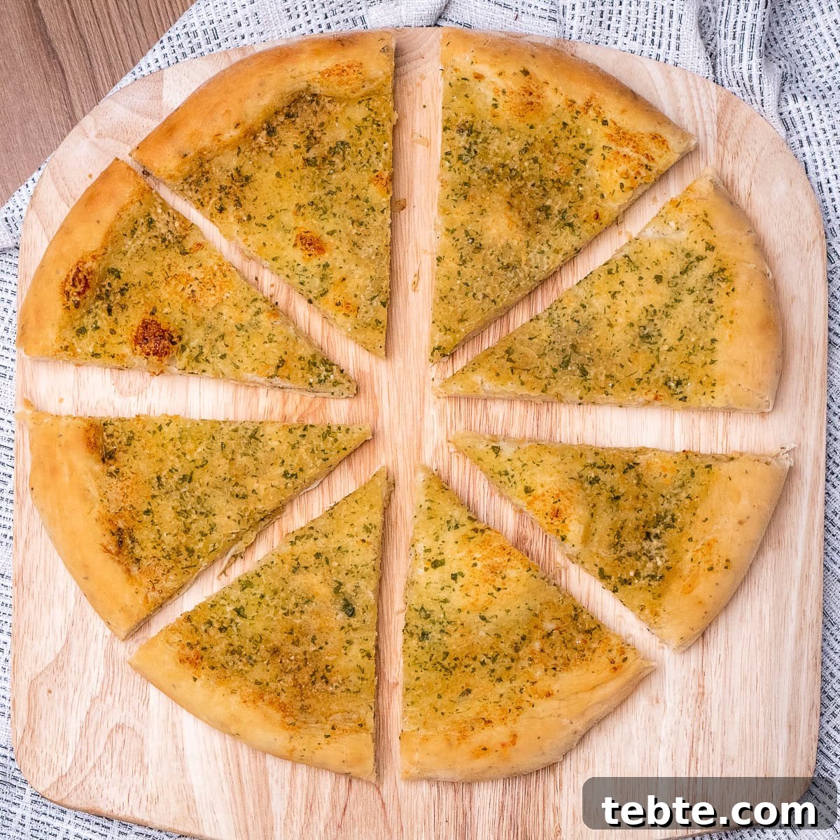 Crispy Garlic Pizza Bread Recipe — Cheesy Garlic Pull-Apart Loaf 3 Garlic Pizza Bread sliced into eight slices on a wooden pizza board