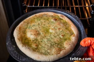 Crispy Garlic Pizza Bread Recipe — Cheesy Garlic Pull-Apart Loaf 15 Taking out a cooked Garlic Pizza Bread out of the oven using an orange oven glove