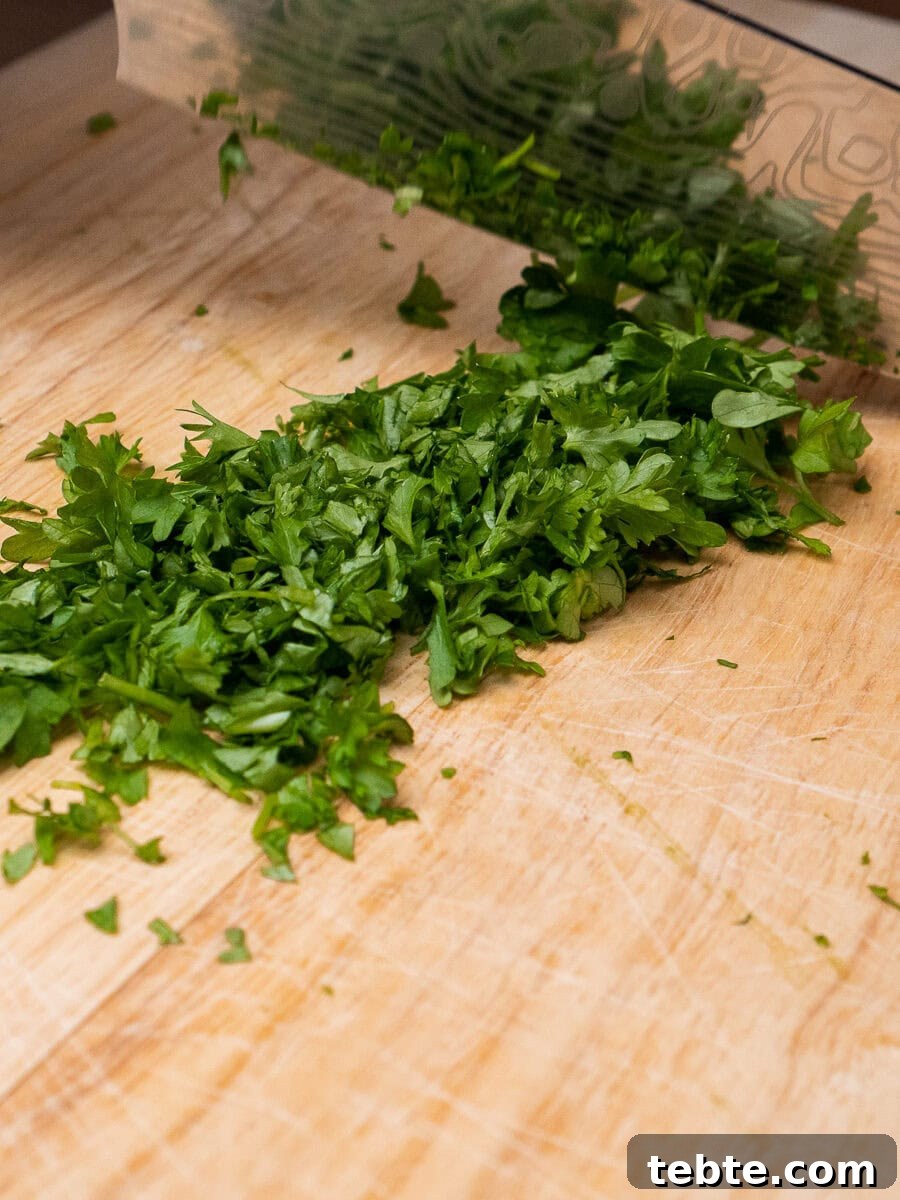 Crispy Garlic Pizza Bread Recipe — Cheesy Garlic Pull-Apart Loaf 22 Chopping up fresh parsley with a knife on a chopping board